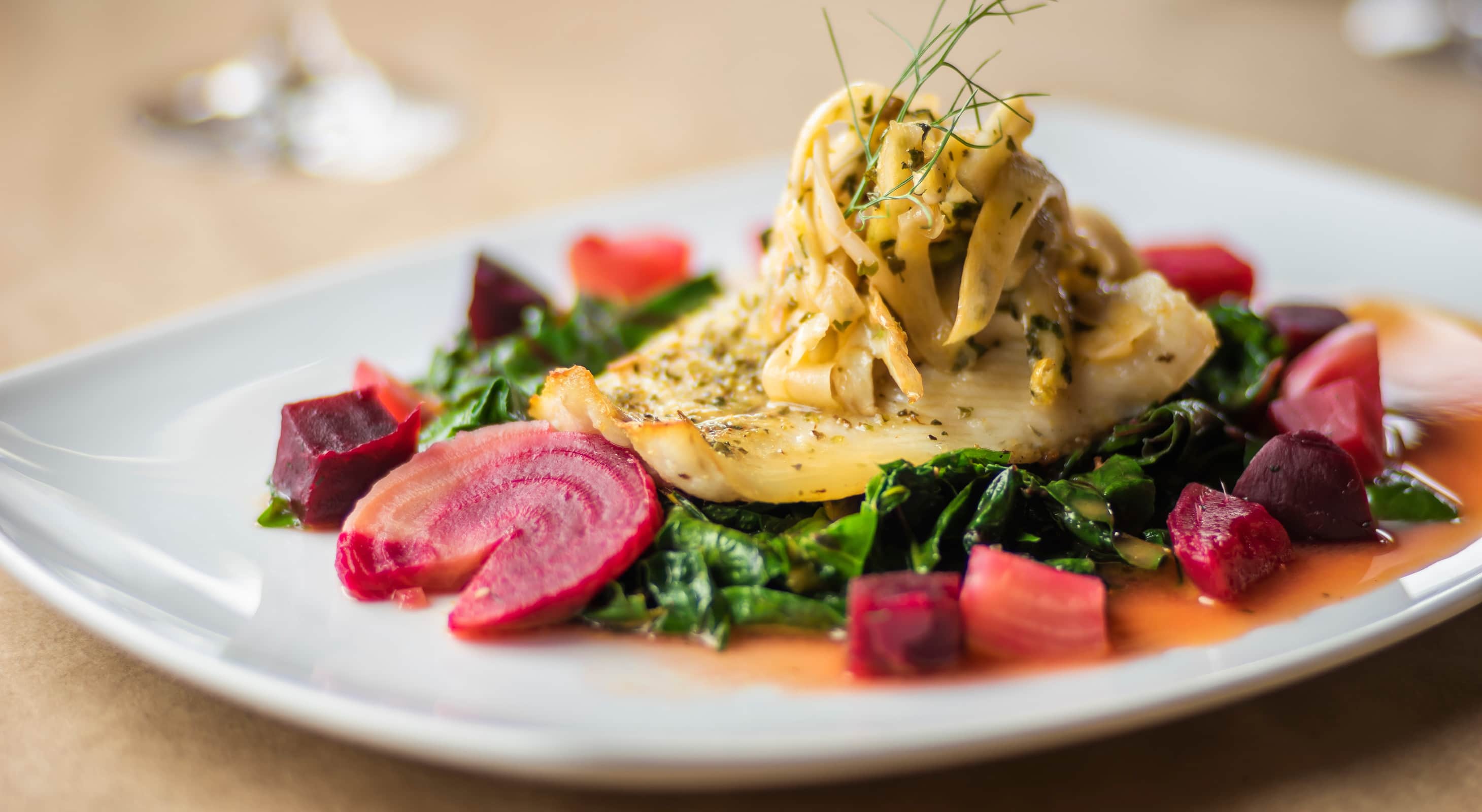 Fish served on a bed of kale and beets